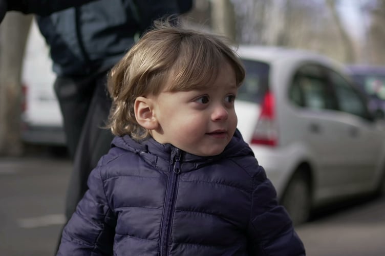 Cute little toddler walking in street sidewalk outside with mom