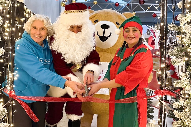 Felicity Edwards from Woking & Sam Beare Hospice helps Santa and a jolly helper officially open Squire’s Woking grotto 